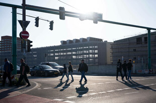 Menschen laufen an der Ampel vor der Ausfahrt der A100 in der Sonnenallee in Berlin-Neukölln