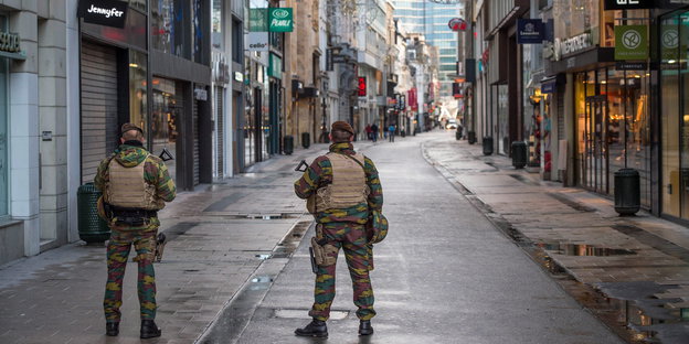 Zwei Soldaten in einer menschenleeren Einkaufsstraße.