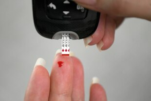 Eine Person misst mit einem Teststreifen ihren Blutzuckerspiegel