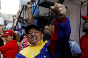 Ein Anhänger Maduros in Venezuela bei einer Protestaktion, hält seine geballte Faust in die Kamera