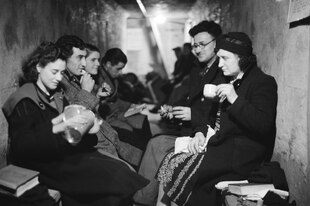 Eine Gruppe von Frauen und Männern sitzt in einem Londoner U-Bahn-Schacht und trinkt Tee, Oktober 1940 Eine Gruppe von Frauen und Männern sitzt in einem Londoner U-Bahn-Schacht und trinkt Tee, Oktober 1940