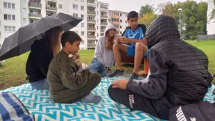 Kinder und Jugendliche sitzen auf einer Picknickdecke