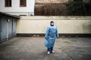 Ein Mensch in Schutzkleidung und mit Atemschutzmaske steh