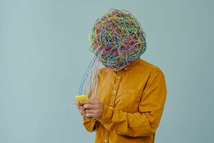 Eine Person mit Kalbeln auf dem Kopf schaut in ein Smartphone