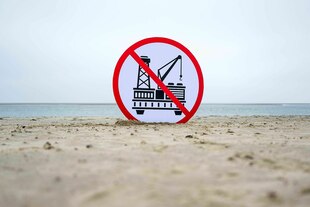 Ein Schild steht auf dem Strand von Borkum, das auf die Ablehnung von Gasbohrungen hinweist