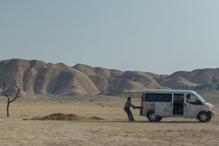 Ein Auto in einer Wüste. Ein Mann zieht einen Menschen von der Ladefläche. Ein Auto in einer Wüste. Ein Mann zieht einen Menschen von der Ladefläche.