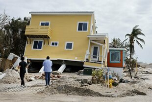 Vom Fundament gehobenes Haus und durch Hurrikan zerstörte Umgebung