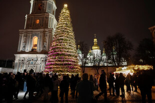 Viele Menschen stehen auf einem Platz um einen geschmückten Weihnachtsbaum herum