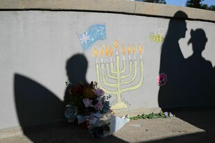Die Schatten von Passanten auf einer Mauer bei einem Gedenkort für die Opfer des Anschlags am Bondi Beach