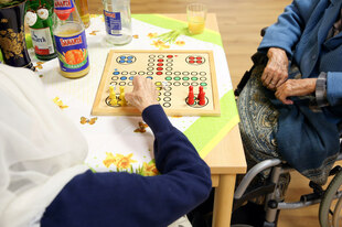 Zwei Seniorinnen, davon mindestens eine mit Hijab, spielen "Mensch ärgere dich nicht". Zwei Seniorinnen, davon mindestens eine mit Hijab, spielen "Mensch ärgere dich nicht".