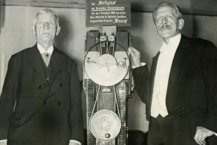 Emil und Max Skladanowsky stehen links und recht neben ihrer Erfindung, dem Filmprojektor "Bioscop".