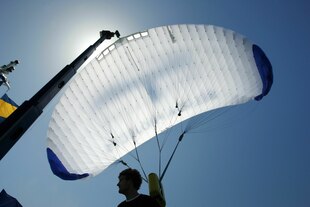 Eine Person steht unter einem Drachen an Bord eines Schiffes