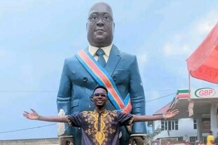 Ein Mann breitet die Arme vor dem Denkmal aus