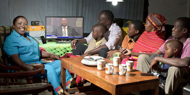 afrikanische Familie am Tisch, auf dem ein Fernseher steht