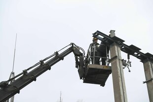 Ein Mann steht auf einer Hebebühne an einem Strommast - und repariert die unterbrochenen Leitungen