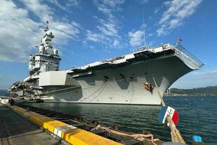 Ein Kriegsschiff liegt am Hafen vor blauem Himmel