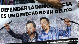 Banner zeigt die beiden inhaftierten Politiker, sie stehen vor einer gemalten Menschenmenge und halten beide das Ende eines Seils in der Hand