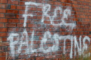 Ein gesprühter Schriftzug an einer Fassade.