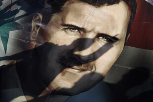 Ein Plakat mit dem Gesicht von Bashar Assad und einem Schatten einer Person davor.
