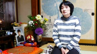 Porträt von Taeko Watanabe mit einem Foto ihres gestorbenen Sohnes.