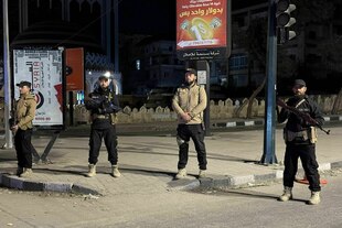Bewaffnete stehen auf einer Straße im Dunkeln.