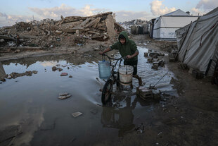 Ein Junge schiebt ein Fahrrad durch einen überschwemmten Weg