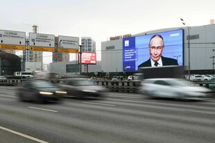 Ein riesiger Bildschirm zeigt Präsident Putin an einer Straße.