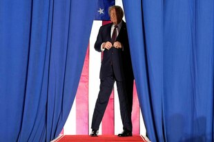 Präsident Donald Trump steht auf einer Bühne halb hinte reinem Vorhang
