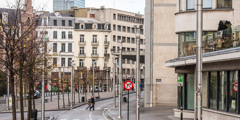 Zwei Fußgänger überqueren eine leere Straße in Brüssel.