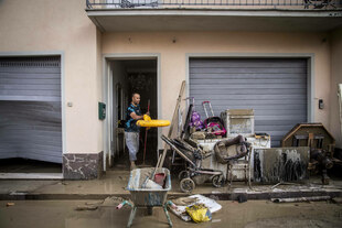 Ein Mann wirft Gegenstände aus einer überschwemmten Wohnung.
