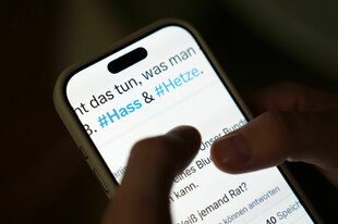 Auf dem Bildschirm eines Smartphones sind in einem Beitrag eines sozialen Netzwerks die Hashtags #Hass und #Hetze zu sehen.