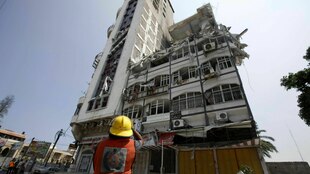 Eine Person betrachtet ein bei einem Angriff zerstörtes Hochhaus.