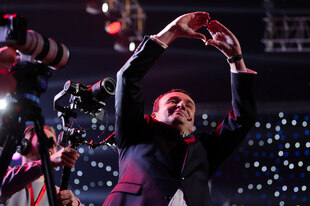 Ein Mann im Anzug formt ein Herz mit seinen beiden Händen