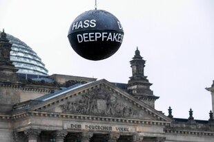 Eine Protestaktion mit einer großen schwarzen Kugel, auf der steht 'Hass - Deepfakes'.