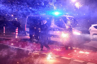 Explodierende Böller neben Polizeibeamten mit Helm