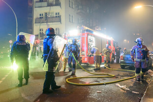 Polizist:innen beschützen einen Feuerwehreinsatz