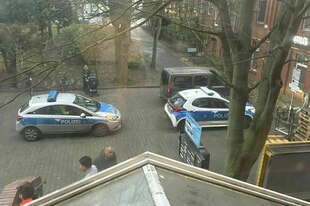 Zwei Polizeiautos stehen vor einem Backsteingebäude
