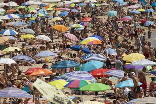 Menschen und Sonnenschirme dicht gedrängt an einem Strand Menschen und Sonnenschirme dicht gedrängt an einem Strand