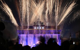 Das Foto zeigt das Brandenburger Tor in der Silvesternacht 2025/2026 erheltt von einem Feuerwerk Das Foto zeigt das Brandenburger Tor in der Silvesternacht 2025/2026 erheltt von einem Feuerwerk
