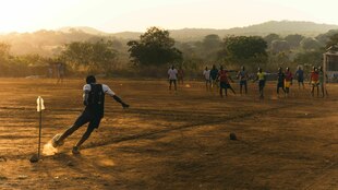 Fußball spielende Jugendliche auf einem Sandplatz Fußball spielende Jugendliche auf einem Sandplatz