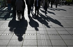 Schatten von Menschen spiegeln sich auf einem gepflasterten Boden