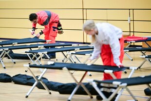 Ehrenamtliche Mitarbeiter des DRK bauen während eines Stromausfalls im Südwesten Berlins in einer Notunterkunft Feldbetten auf. Vom Brand einer Kabelbrücke sind 50.000 Haushalte und 2.000 Gewerbebetriebe betroffen. Ehrenamtliche Mitarbeiter des DRK bauen während eines Stromausfalls im Südwesten Berlins in einer Notunterkunft Feldbetten auf. Vom Brand einer Kabelbrücke sind 50.000 Haushalte und 2.000 Gewerbebetriebe betroffen.