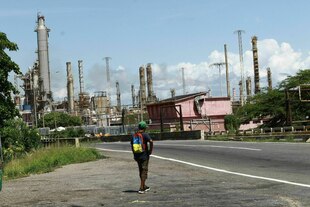 Eine Person läuft auf einer Straße, die vor einer Ölraffinerie entlangführt Eine Person läuft auf einer Straße, die vor einer Ölraffinerie entlangführt