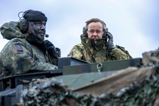 Boris Pistorius und ein Bundeswehroffizier auf einem Panzer