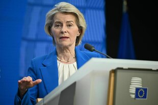 Eine Frau mit blauer Jacke steht an einem Rednerpult.