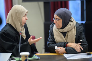 Zwei Frauen mit Kopftuch sitzen nebeneinander im Gerichtssaal und besprechen etwas. Es handelt sich um die Mutter des Mordopfers Rahma Ayat und die Anwältin, die sie als Nebenklägerin vertritt.
