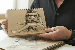 Eine Person zeigt eine Zeichnung von einem Paar beim Sex