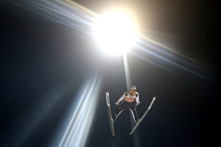 Domen Prevc wird im Nachthimmel beim Sprung vom Flutlicht bestrahlt