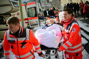 Rettungssanitäter evakuieren eine bettlägrige Bewohnerin aus einer Notunterkunft während des Stromausfalls