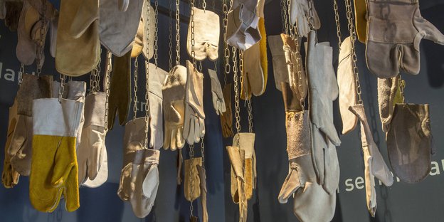 Lederhandschuhe hängen an Ketten von einer Decke